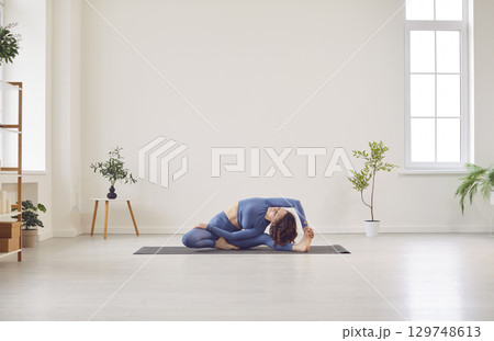 Sporty beautiful young woman practicing yoga, doing Janu Sirsasana, Head-to-Knee Forward Bend Pose Sporty beautiful young woman practicing yoga, doing Janu Sirsasana, Head-to-Knee Forward Bend Pose 129748613