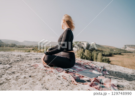 Woman in Black Outfit Sitting on a Rock with a Blanket in a Mountainous Landscape Woman in Black Outfit Sitting on a Rock with a Blanket in a Mountainous Landscape 129748990