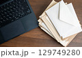 ノートパソコンと積み重なった封筒の山 129749280
