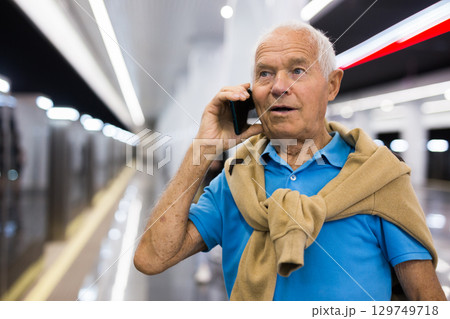 Old man with smartphone in subway station Old man with smartphone in subway station 129749718