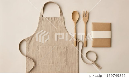 Cooking apron, utensils, and neatly wrapped package on a light background ready for meal preparation 129749833