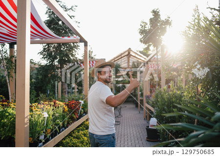 Garden store employee taking care of plants. Garden store employee taking care of plants. 129750685