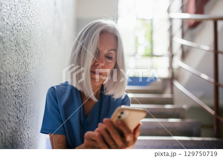 Tired nurse taking break during hospital shift, texting with family. Tired nurse taking break during hospital shift, texting with family. 129750719