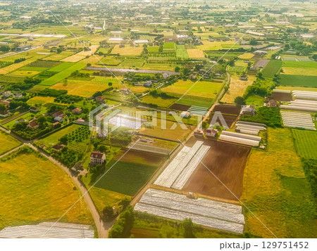 Countryside landscape with greenhouses and rural homes in summer sunlight. Agricultural development, residential harmony, and productive land use in southern Europe. Countryside landscape with greenhouses and rural homes in summer sunlight. Agricultural development, residential harmony, and productive land use in southern Europe. 129751452