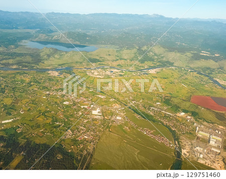 Aerial view of lake and farmlands near mountain range. Water resources, agricultural development, and diverse natural topography. 129751460