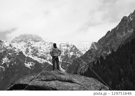 asian man standing on top of rock looking at peak of snow mountain 129751646