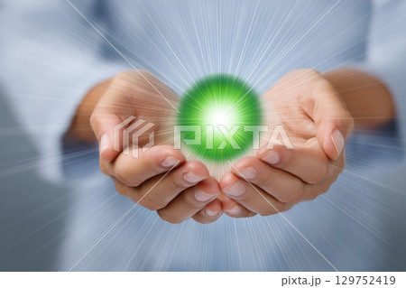 Gentle Hands Cupping a Green Glowing Energy Orb with Radiant Light in a Serene Environment 129752419