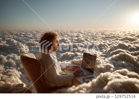 Serene Futuristic Workspace Above the Clouds with Focused Individual at a Desk Using Laptop 129752514