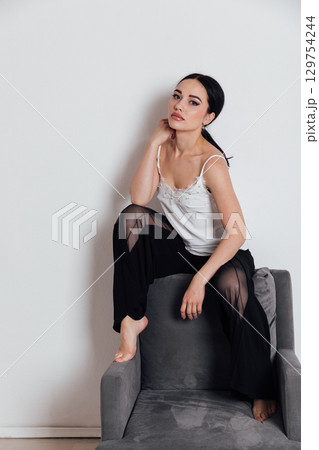 Portrait of a beautiful brunette woman sitting in an empty room Portrait of a beautiful brunette woman sitting in an empty room 129754244