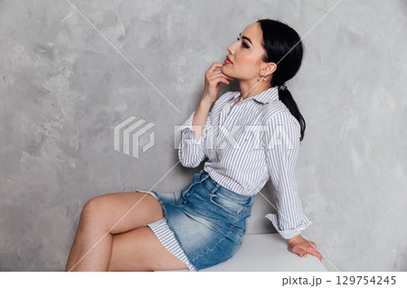 Portrait of a beautiful brunette woman sitting in an empty room 129754245