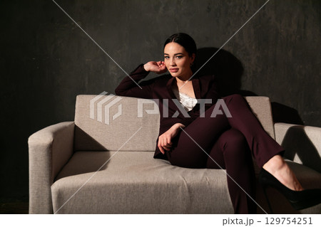 woman in business suit sitting on gray office sofa 129754251