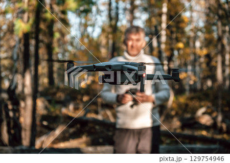 man pilots drone through an autumn forest showcasing modern technology in nature. closeup. 129754946