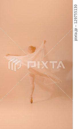 Graceful ballerina with flowing fabric dancing on pointe in soft pastel tones 129755130
