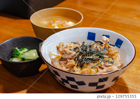 鶏肉と玉ねぎの丼ぶりに味噌汁と漬物を添えた和風夕食セット 鶏肉と玉ねぎの丼ぶりに味噌汁と漬物を添えた和風夕食セット 129755355