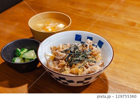 鶏肉と玉ねぎの丼ぶりに味噌汁と漬物を添えた和風夕食セット 鶏肉と玉ねぎの丼ぶりに味噌汁と漬物を添えた和風夕食セット 129755360