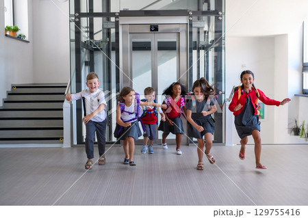 Happy schoolkids in uniforms running down the school hallway. Happy schoolkids in uniforms running down the school hallway. 129755416