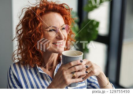A portrait of businesswoman resting in an office, holding a cup of coffee. A portrait of businesswoman resting in an office, holding a cup of coffee. 129755450