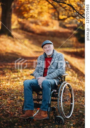 Pensive older man in wheelchair in the middle of autumn nature. Pensive older man in wheelchair in the middle of autumn nature. 129755468