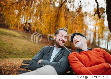 Grandad and grandson sitting on bench in park and talking. Grandad and grandson sitting on bench in park and talking. 129755484