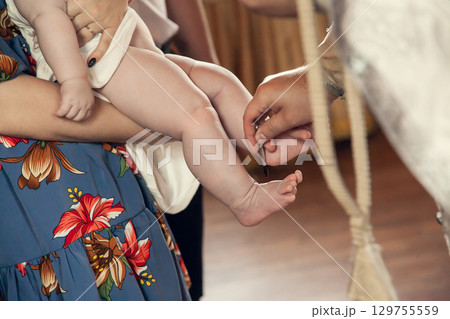 The sacrament of baptism in the Orthodox Church. The priest anoints the child's feet with oil 129755559
