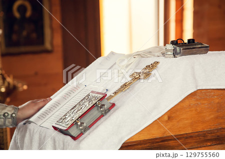 The sacrament of baptism in the Orthodox Church. Prayer books and a crucifix on the table 129755560