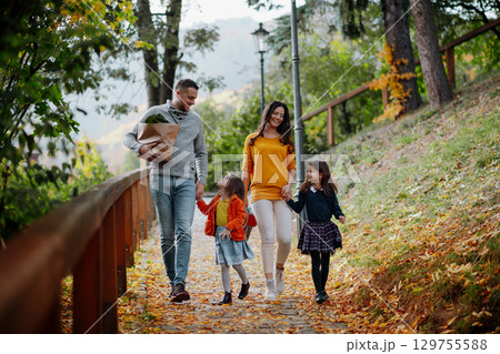 Sisters and parents walking in park during warm autumn day. Sisters and parents walking in park during warm autumn day. 129755588