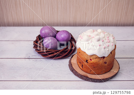 Easter cakes decorated marshmallows, and painted Easter eggs in a wicker nest on a light wooden background Easter cakes decorated marshmallows, and painted Easter eggs in a wicker nest on a light wooden background 129755798