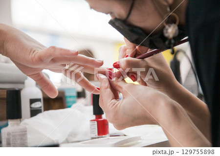 Gel polish design. Female master in the salon is painting with brush on the hands of the client. Beauty industry, creativity concept Gel polish design. Female master in the salon is painting with brush on the hands of the client. Beauty industry, creativity concept 129755898