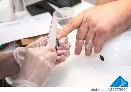 Men's manicure. A manicure master files the nails of a man in a beauty salon. Beauty industry 129755902