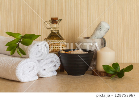 Spa, beauty and wellness background: towel, cosmetic massage oil, fresh leaf, sea salt with shells and candle Spa, beauty and wellness background: towel, cosmetic massage oil, fresh leaf, sea salt with shells and candle 129755967