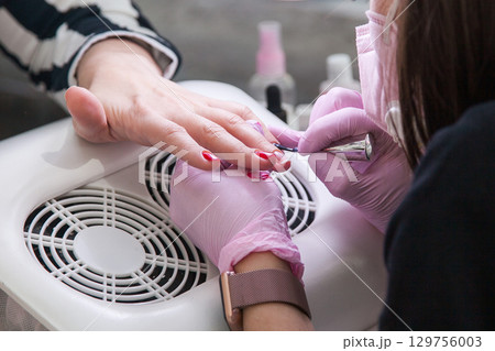 Gel polish design. Female master in the salon is painting with brush on the hands of the client. Beauty industry, creativity concept Gel polish design. Female master in the salon is painting with brush on the hands of the client. Beauty industry, creativity concept 129756003