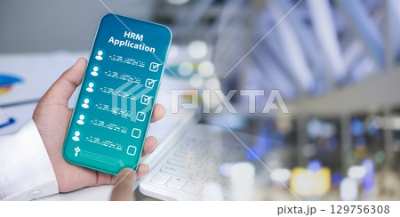 Human hand holding smartphone with HRM app checklist for modern human resource management, workplace technology, digital transformation, mobile HR solutions, and business innovation. Human hand holding smartphone with HRM app checklist for modern human resource management, workplace technology, digital transformation, mobile HR solutions, and business innovation. 129756308