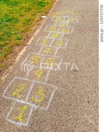 A hopscotch game drawn with chalk on the pavement in the park. Childhood, nostalgia and playful leisure activity connecting imagination with movement and joy. A hopscotch game drawn with chalk on the pavement in the park. Childhood, nostalgia and playful leisure activity connecting imagination with movement and joy. 129757356