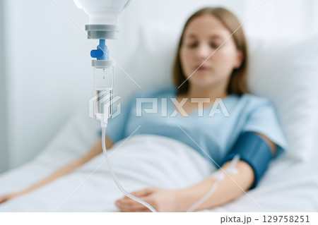Young woman receiving medical treatment with iv drip in hospital room focused on healthcare professionalism and patient care concept of recovery, hospital environment 129758251