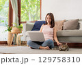 Woman using laptop and playing with cat 129758310