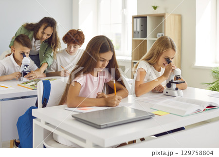 School class at lesson, female teacher and pupil friends learning, group of busy schoolchildren 129758804