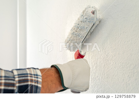House painter worker painting a wall white. Building. 129758879