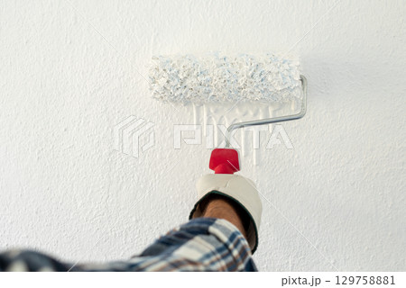 House painter worker painting a wall white. Building. House painter worker painting a wall white. Building. 129758881