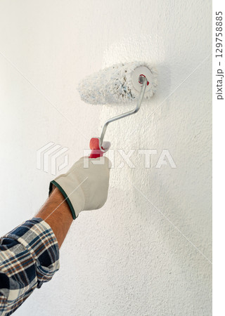 House painter worker painting a wall white. Building. House painter worker painting a wall white. Building. 129758885