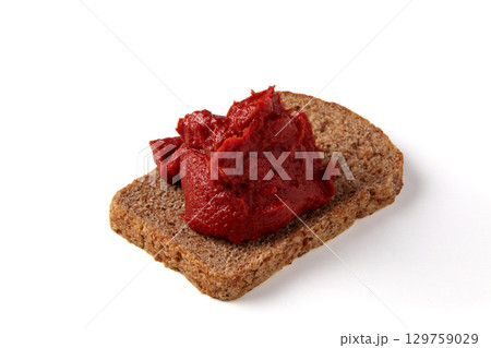 pile of tomato paste on a piece of rye bread isolated on white background. 129759029