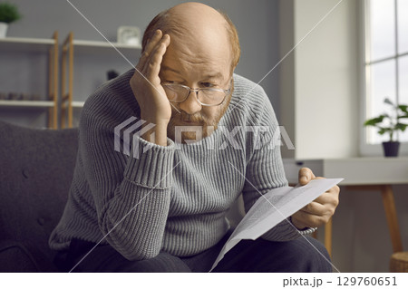 Sad senior man holding a letter from the bank and thinking about his financial problems 129760651
