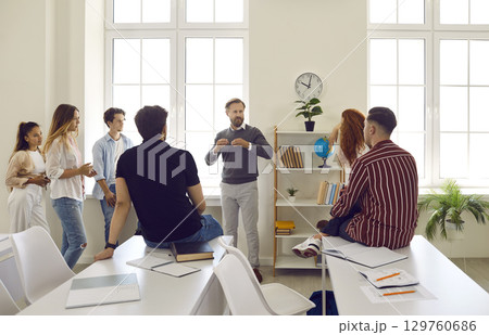 Male professor having informal conversation with students during break in classroom 129760686