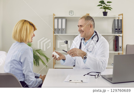Mature male doctor consulting female patient at his office 129760689