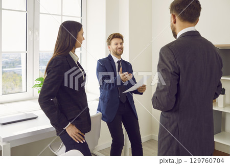Company employees standing on workplace and discussing work project on a meeting in the office. 129760704