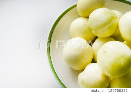 Ripe yellow plum in a green bowl. Juicy fruit on a white background. Ripe plums in drops of water. Ripe yellow plum in a green bowl. Juicy fruit on a white background. Ripe plums in drops of water. 129760821