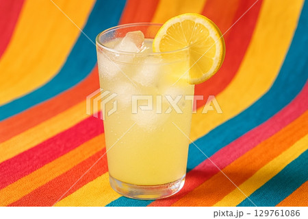 Refreshing lemonade with ice in a glass on a vibrant striped background. concept of summer refreshment, chilled drink, bright colors. 129761086