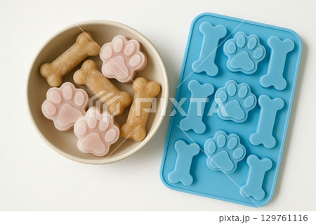 Frozen treats for dogs in bone and paw shapes to keep pets cool and happy during summer. concept of pet care, dog snacks, summer treats 129761116
