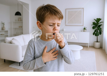Young child coughing at home in a cozy living room environment. concept of child health, home comfort, illness care, everyday childhood experience. 129761251