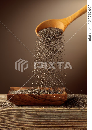Chia seeds is poured into a wooden bowl. 129762003