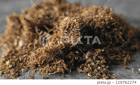 Dry tobacco leaves piled on a gray surface 129762274